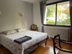 um quarto com uma cama e uma grande janela em Les jardins de l'Hermitage em Cellettes