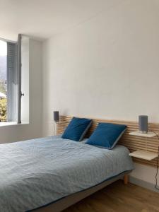 a bedroom with a large bed with blue pillows at La Parisette in La Bourboule
