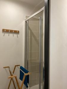 a glass shower in a bathroom with a chair at La Parisette in La Bourboule