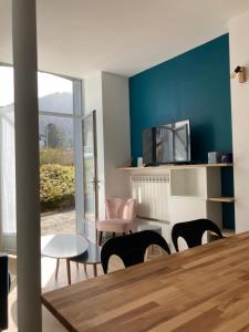 a living room with a table and chairs and a tv at La Parisette in La Bourboule