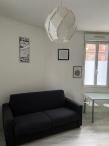 a living room with a black couch and a table at CosyRouen Gare in Rouen