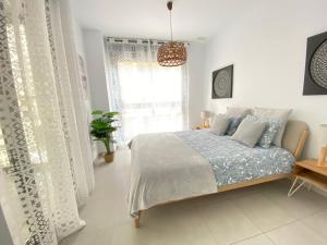 a white bedroom with a bed and a window at Calpe Beach II - sea & pool view apartment in Calpe