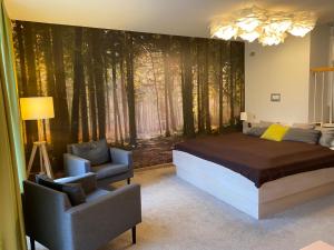 a bedroom with a bed and chairs and a forest mural at Ferienwohnungen auf Halbinsel Scheid in direkter Ufernähe in Scheid