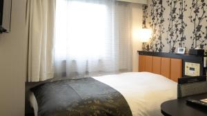 um quarto com uma cama e uma janela com cortinas em APA Hotel Saitama Higashimatsuyama Ekimae em Matsuyama