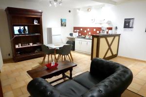 a living room with a leather couch and a table at Appart' de la collégiale in Bourbon-Lancy