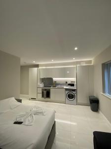 a white room with a bed and a kitchen at Buckingham Apartments in High Wycombe