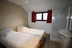 - une petite chambre avec 2 lits et un lavabo dans l'établissement Hôtel Le Tuc de l'Etang, à Boutx