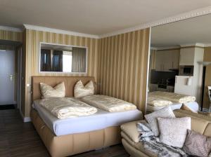 1 dormitorio con 2 camas y sofá en Tiffanys Ferienapartments in der Privatresidenz des Plaza Premium Hotel Timmendorfer Strand, en Timmendorfer Strand