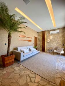 a living room with a couch and a palm tree at Maré Loft Praia in Icaraí