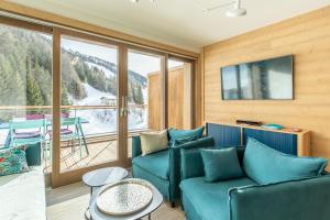 d'un salon avec un canapé et un balcon. dans l'établissement LE RIDGE Résidence Premium - Les Arcs Paradiski, à Arc 1600