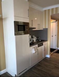 a kitchen with white cabinets and a microwave at Tiffanys Ferienapartments in der Privatresidenz des Plaza Premium Hotel Timmendorfer Strand in Timmendorfer Strand