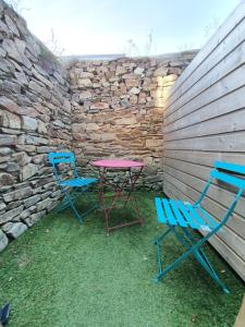 two chairs and a table next to a stone wall at Appartements C'Home un charme in Lannion