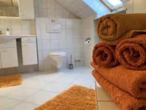 a bathroom with a toilet and a pile of towels at 2 - Zimmer Wohnung in Hilter am Teutoburger Wald
