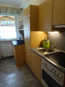 cocina con armarios de madera, fregadero y ventana en Appartement Klotz en Längenfeld