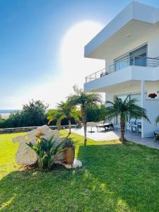 a white house with a yard with palm trees at Villa Proistakis in Achlia
