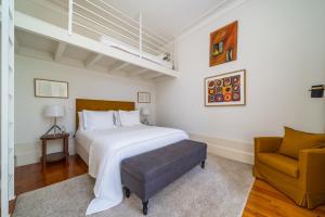 a bedroom with a large white bed and a chair at Casa do Cativo in Porto