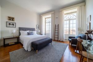 a bedroom with a bed and a chair and windows at Casa do Cativo in Porto