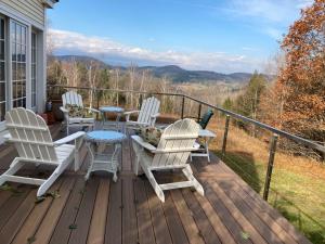 a deck with white chairs and a table with a view at The Birch Grove in Woodstock