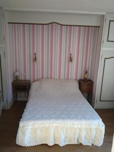 een slaapkamer met een bed met een gestreepte muur bij Gîte du Moulin de la Roque in Castels