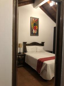 a bedroom with a bed and a picture on the wall at Hotel Mansion Del Rey in Antigua Guatemala