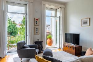 a living room with a couch and chairs and a television at Casa do Cativo in Porto