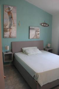 un dormitorio con una cama y una pintura de una mujer en La Casetta del Mirto Paduledda, en Isola Rossa