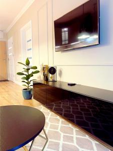 a living room with a table and a tv on the wall at Apartament Braniborska in Wrocław