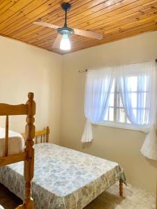 1 dormitorio con 1 cama, ventilador de techo y ventana en Apartamentos Vitali en Imbé