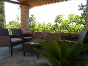 a patio with chairs and a stone wall at Le Mas des Monèdes in Saint-Paul-le-Jeune