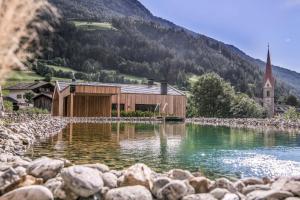 a house on the shore of a lake with a church at Chalet & Appartement Zingerlehof Trens in Campo di Trens