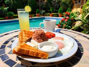 a plate of breakfast food on a table with a drink at Hotel Los Pinos in Managua