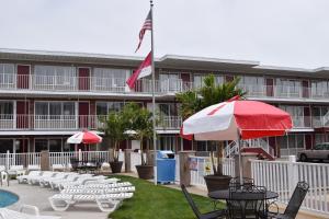 a hotel with tables and umbrellas and a pool at Hershey Motel in Seaside Heights