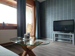 uma sala de estar com uma mesa de vidro e uma televisão em LAAX Central Holiday Apartment with Pool & Sauna em Laax