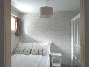 um quarto com uma cama com lençóis brancos e um candeeiro em LAAX Central Holiday Apartment with Pool & Sauna em Laax