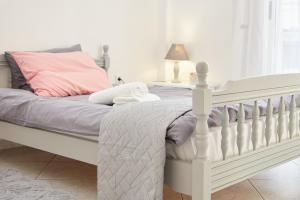 a bedroom with a white bed with a pink pillow at APARTMENT in XANTHI My home in Xanthi