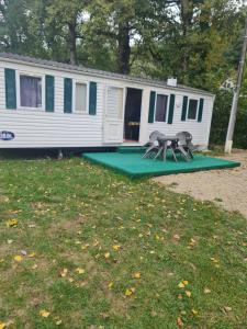 a mobile home with two picnic tables in front of it at Camping de la mothe in Banassac