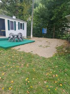 two picnic tables on a green mat in a yard at Camping de la mothe in Banassac +1 photo