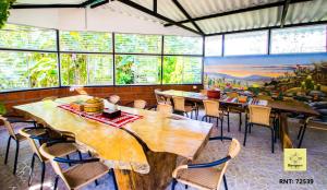 un restaurante con mesas y sillas de madera y ventanas en Bosques de la Pradera en Manizales