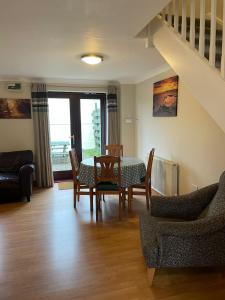 ein Wohnzimmer mit einem Tisch, Stühlen und einer Treppe in der Unterkunft Rose Cottage in Camelford