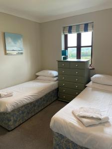 a bedroom with two beds and a dresser and a window at Rose Cottage in Camelford