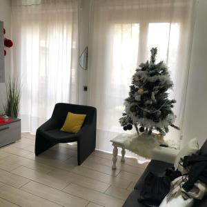 ein Wohnzimmer mit einem Weihnachtsbaum und einem Stuhl in der Unterkunft CASA ROSI trequattrozerotrentatretrediciseiquattrouno in Umbertide