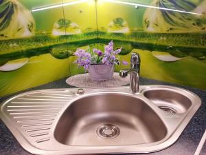 a sink with a vase of flowers on a counter at M&M Apartment II SELF CHECK-IN in Panevėžys