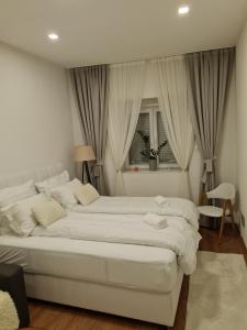 1 cama blanca grande en un dormitorio con ventana en Dino en Sarajevo