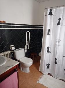 a bathroom with a toilet and a black and white shower curtain at Casa rural "La Bodega" in Cehegín