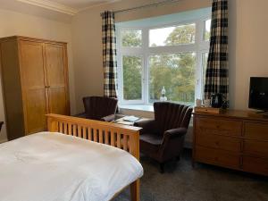 
a bedroom with a bed, chair, desk and television at Shandwick House in Tain
