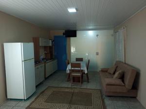 a kitchen with a couch and a table and a refrigerator at Apartamentos Zidane in Gramado