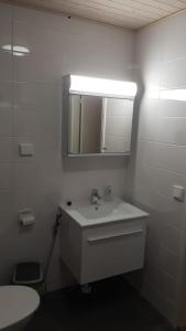 Un baño blanco con lavabo y espejo. en Lehtikatu Apartments, en Rovaniemi 8 fotos más