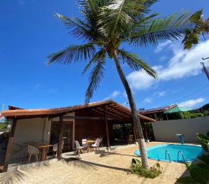 a villa with a palm tree and a swimming pool at Pousada Alma Noronha in Fernando de Noronha