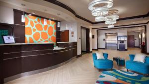 a lobby with two blue chairs and a reception desk at Best Western Premier Ashton Suites - Willowbrook in Houston