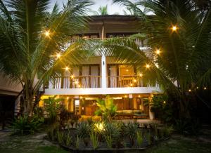 a hotel with palm trees in front of it at night at Lagkaw Siargao Villas in General Luna